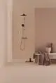 Duschsystem von Ideal Standard mit zwei Peitschengriffen und einer modernen, minimalistischen Optik. Montiert an einer beige Wand, ergänzt durch schlichte Badezimmeraccessoires.